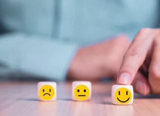 Businessman chooses a smile emoticon icons face happy symbol on wooden block , Services and Customer satisfaction survey concept