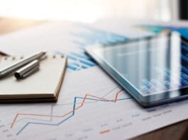 Business document report on paper and tablet with sales data and financial business growth graph on table background.