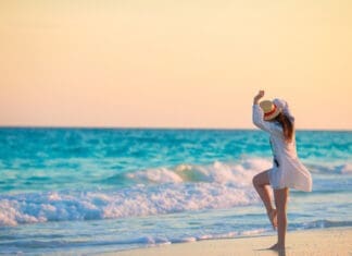 Young happy woman in swimsuit on white beach