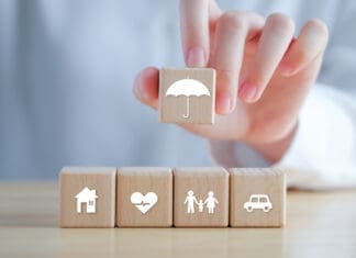 Insurance concept. Protection against a possible eventuality. Hand holding umbrella icon and House, Car, Family and Health icon on wooden block for assurance life concept.