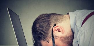 Stressed man lying on laptop