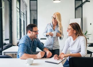 Three casual business people laughing and having fun at training seminar.